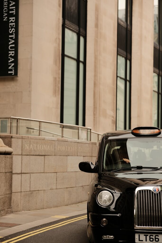 A black taxi cab driving down a street next to tall buildings