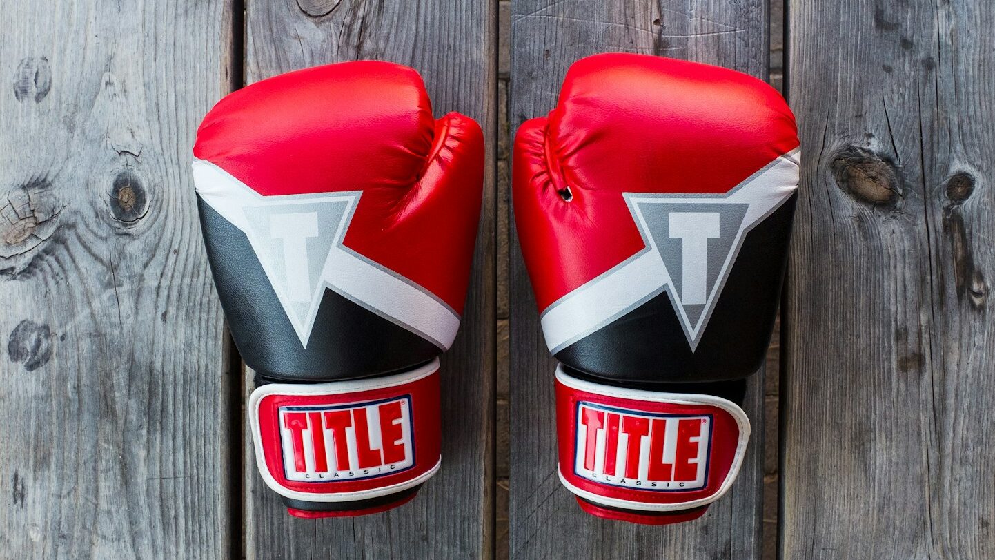 pair of red-and-black Title training gloves on grey wooden plank